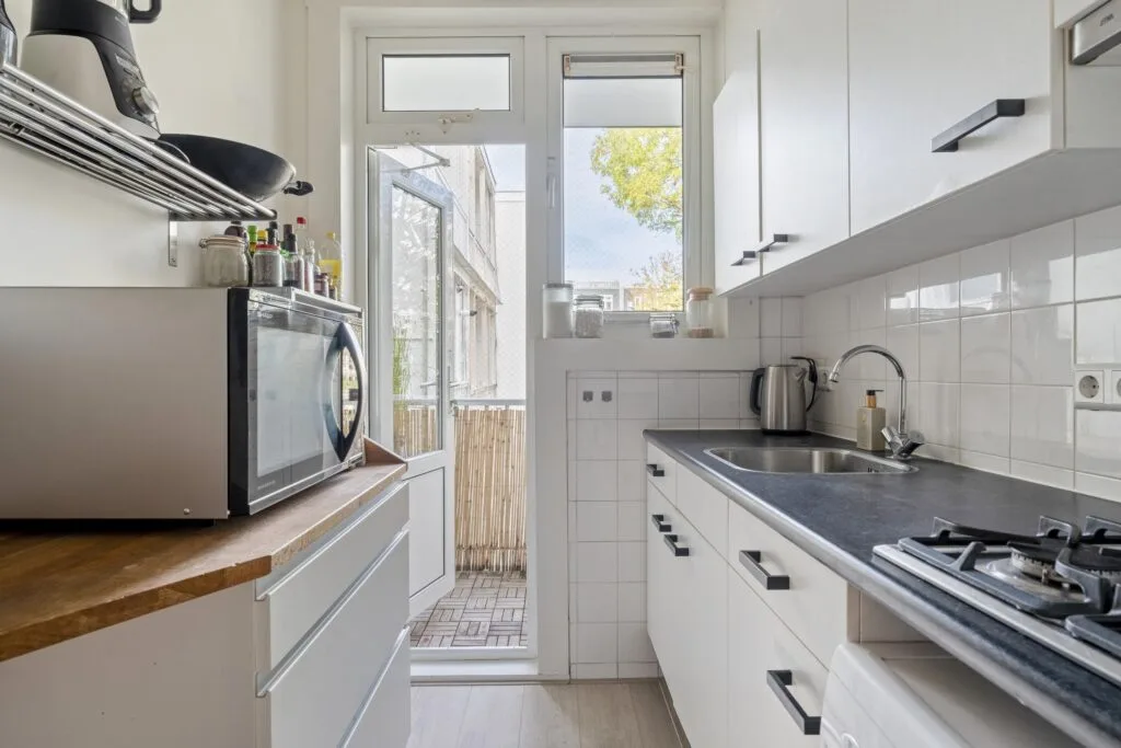 Modern kitchen with appliances and balcony view.