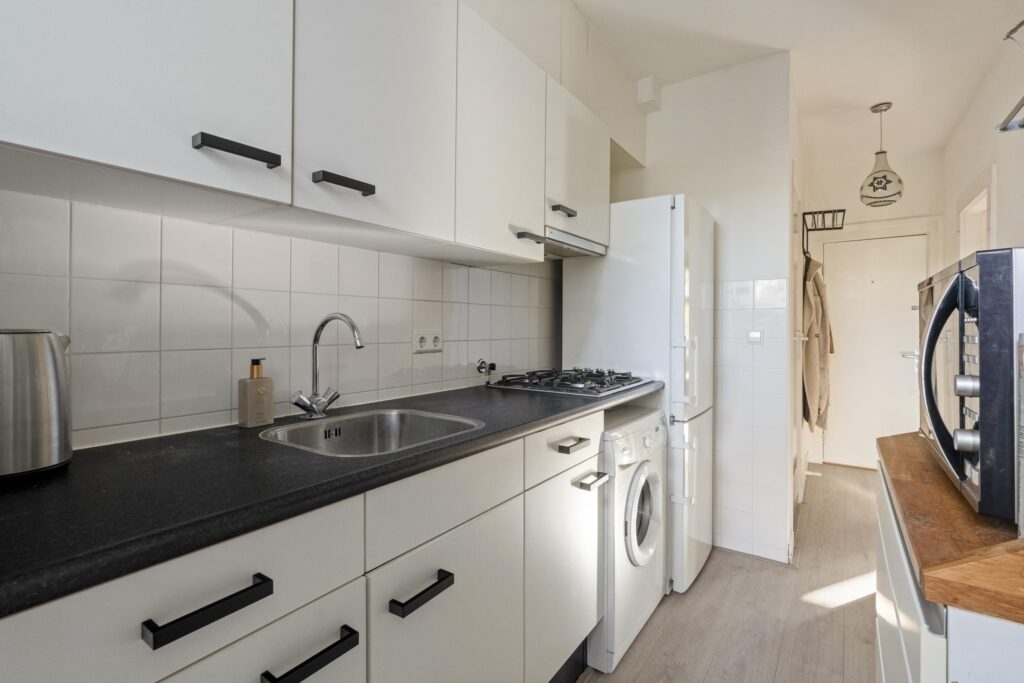 Modern kitchen with white cabinets and appliances.