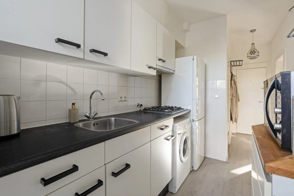 Modern kitchen with white cabinets and appliances.