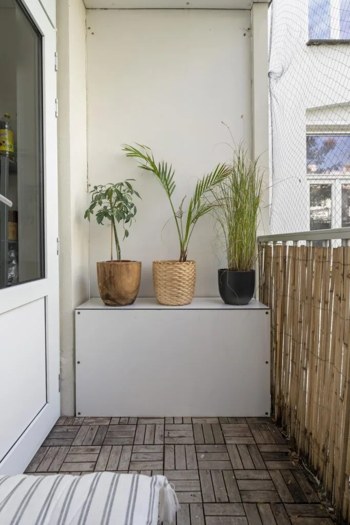 Small balcony with potted plants and wooden floor.