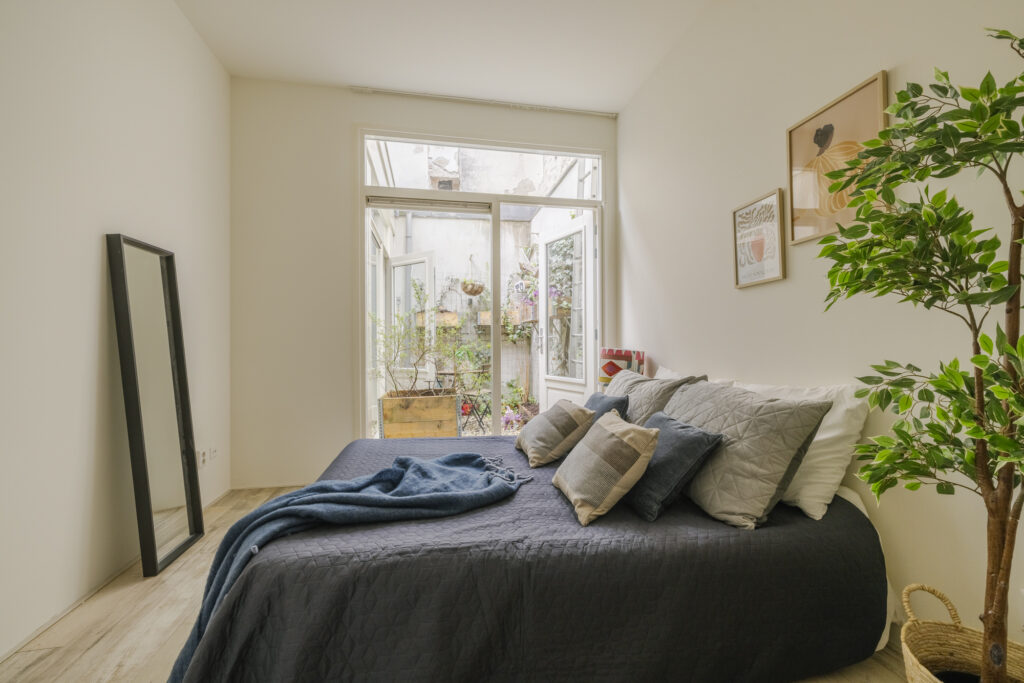 Cozy bedroom with large windows and plants.