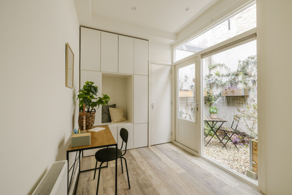 Minimalist study with garden view, wooden desk and chair.