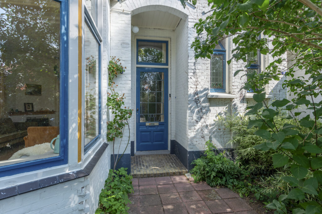 Blue door of white brick house with greenery