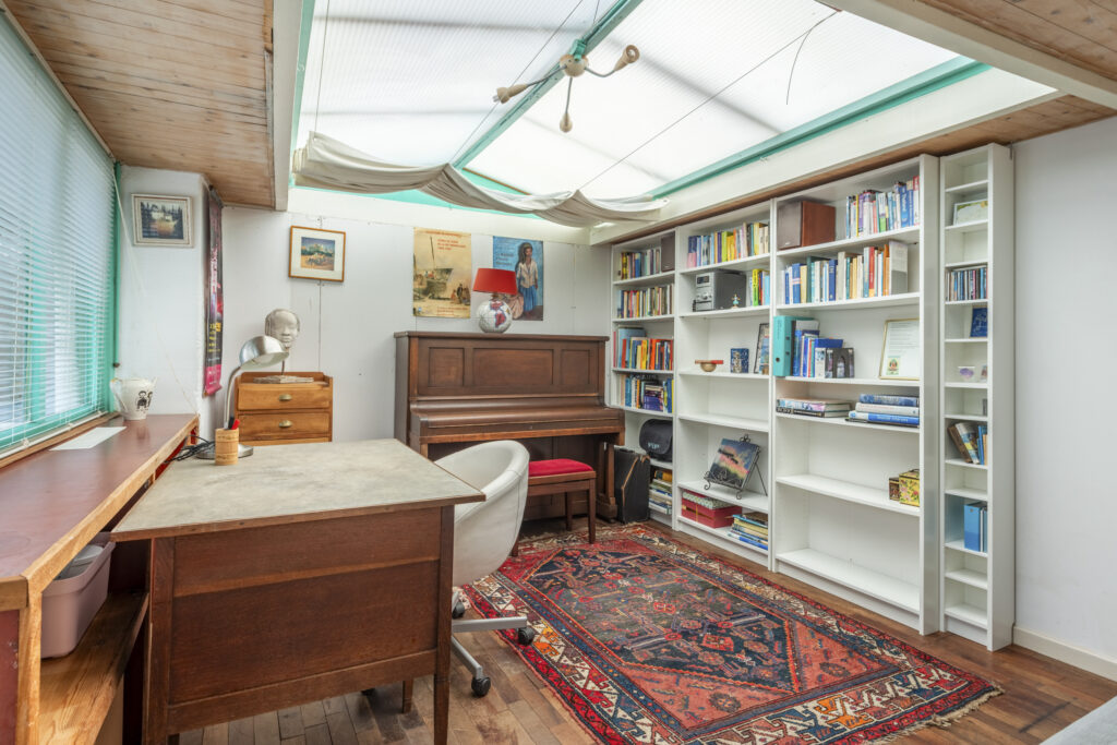 Cozy home office with piano and bookshelves.
