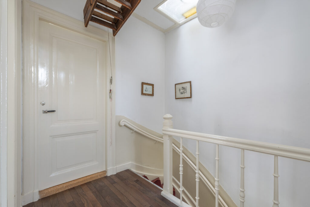 White stairwell with wooden attic ladder.