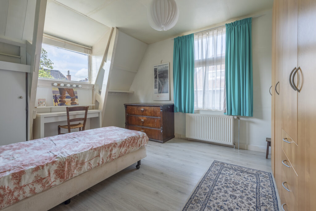 Cozy bedroom with desk and window view.