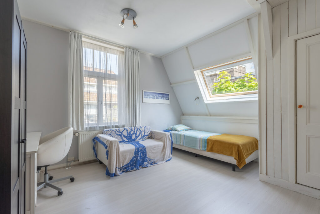 Cozy bedroom with bed, window, and small sofa.