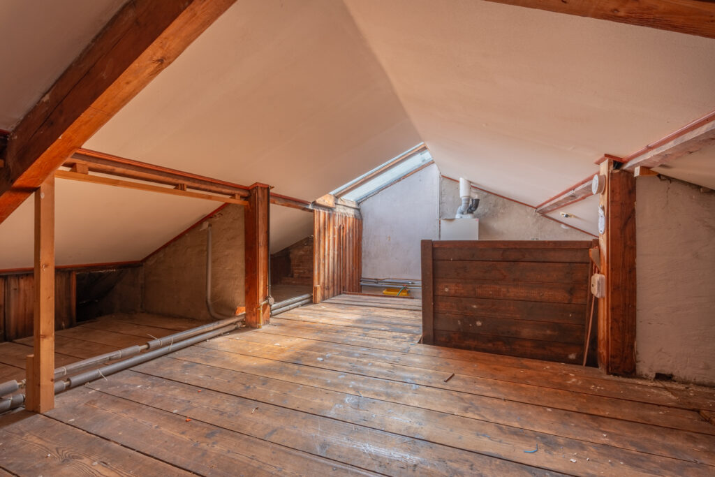 Spacious attic with wooden beams and floorboards.