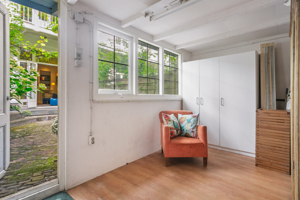 Cozy room with orange chair near open door.