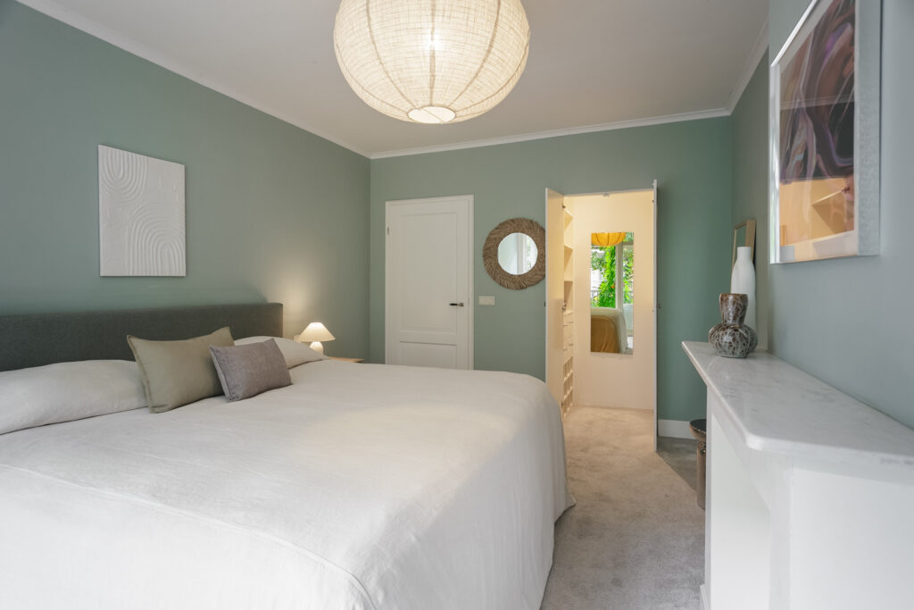 Modern bedroom with green walls and large bed.