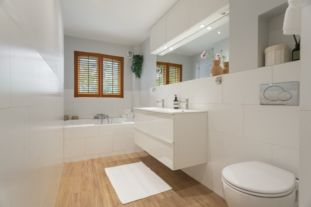 Modern bathroom with wooden flooring and white fixtures.