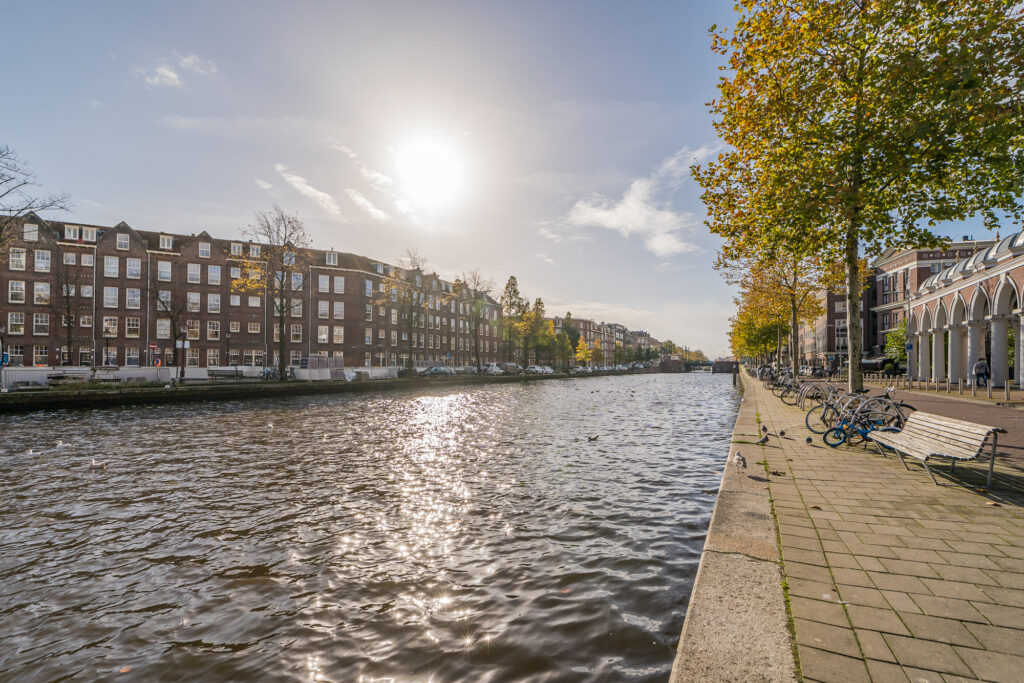 Sunny day by Amsterdam canal with bicycles.