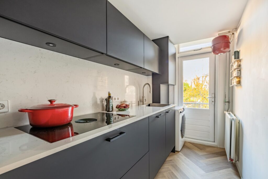 Modern kitchen with red pot on stove.
