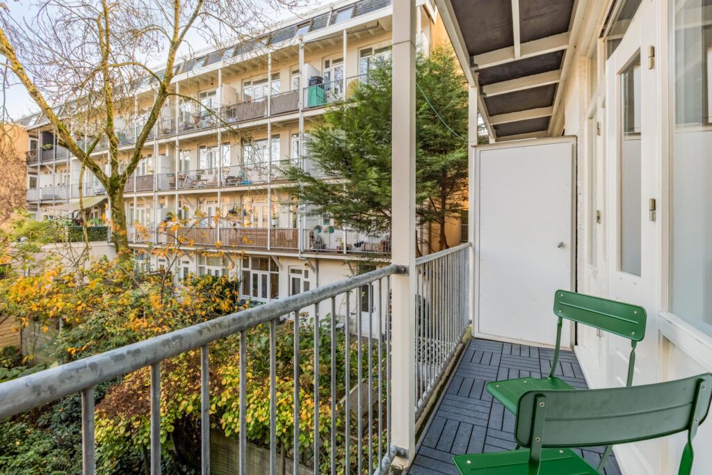 Apartment balcony with green chair and leafy view