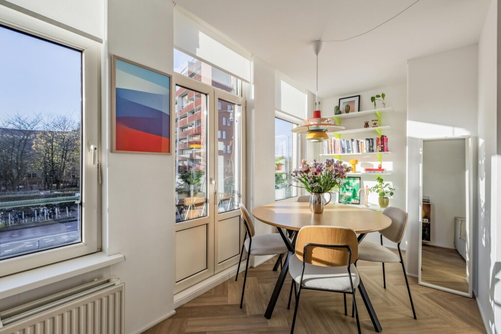 Bright dining area with round table and shelves.