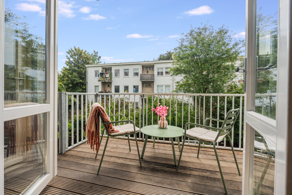 Cozy balcony with chairs, table, flowers, and view.