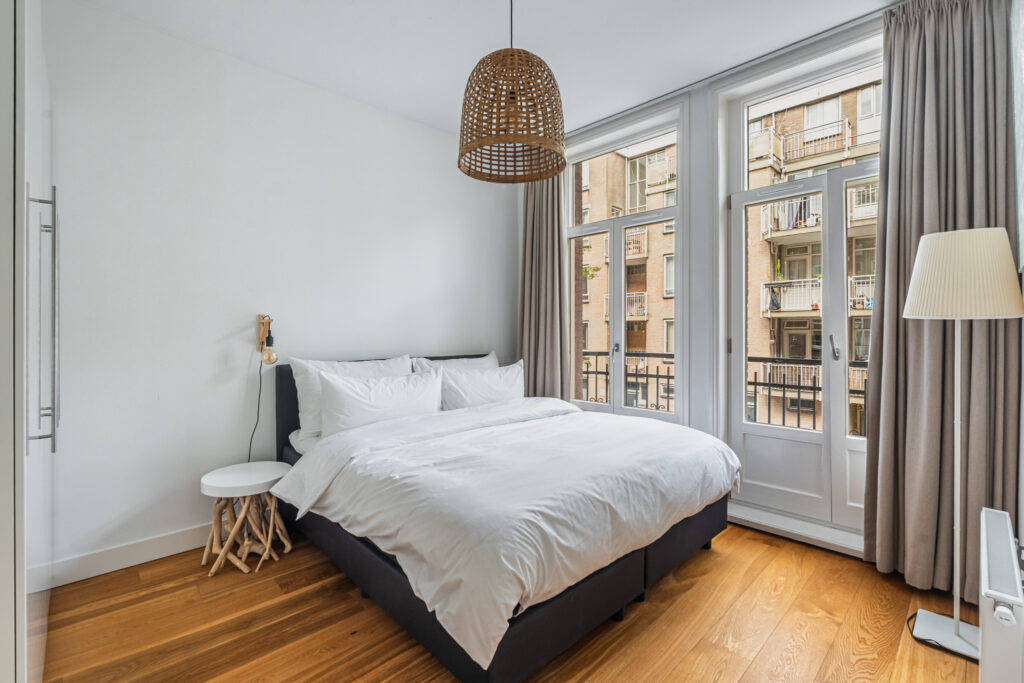 Modern bedroom with wood floors and large windows