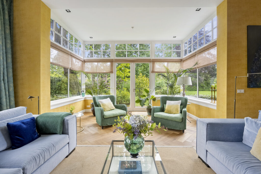 Bright living room with green chairs and large windows.