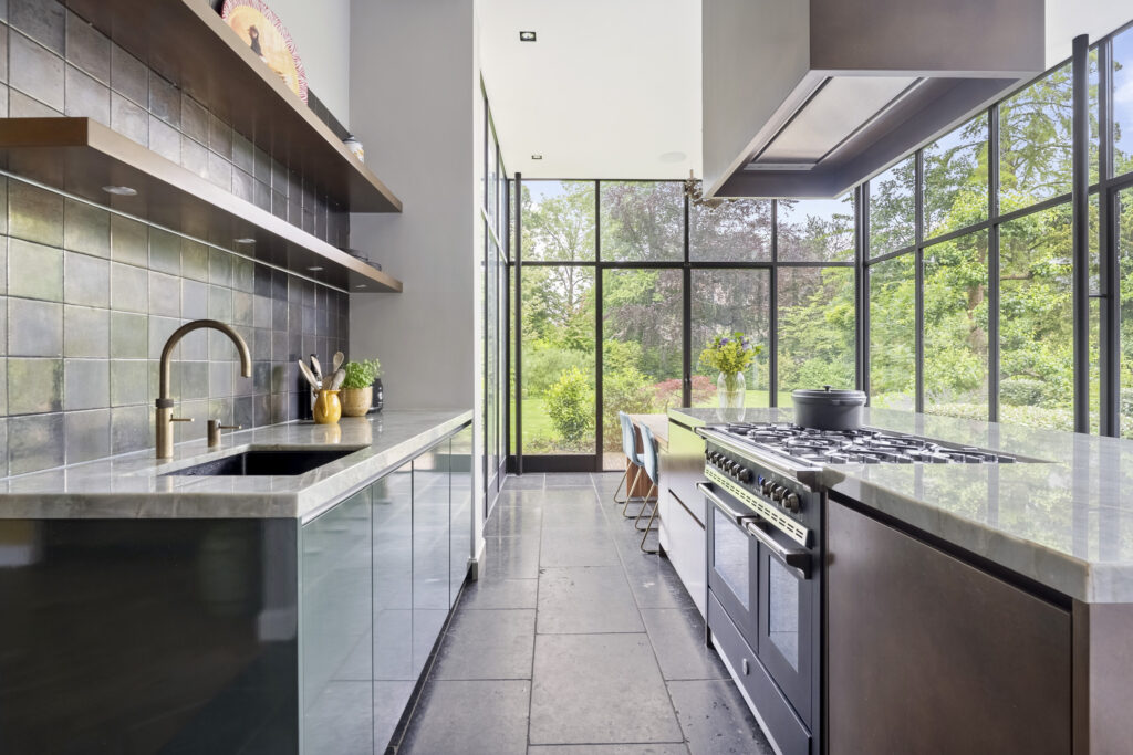 Modern kitchen with large glass windows overlooking garden.