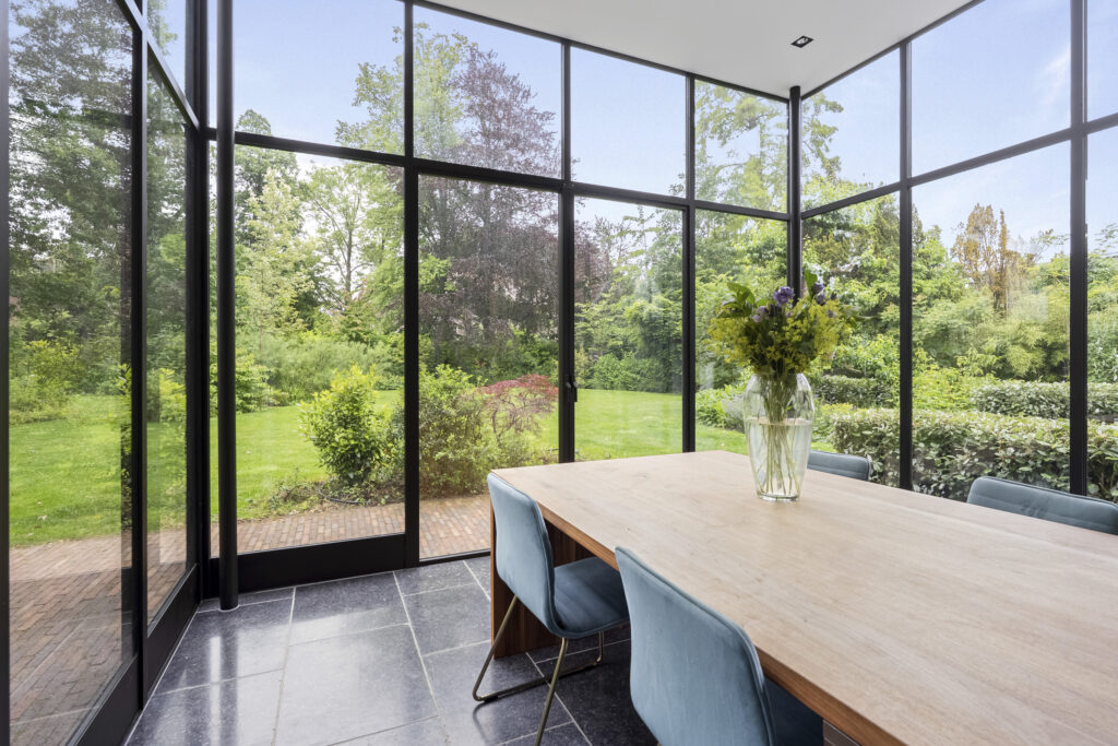 Bright dining room with garden view through glass walls.