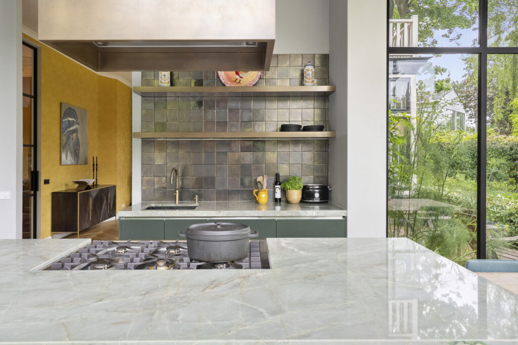 Modern kitchen with marble countertops and garden view.