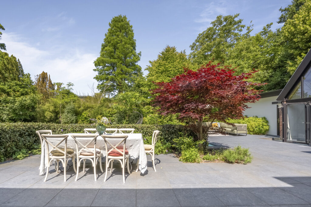 Outdoor dining area with table and chairs in garden.