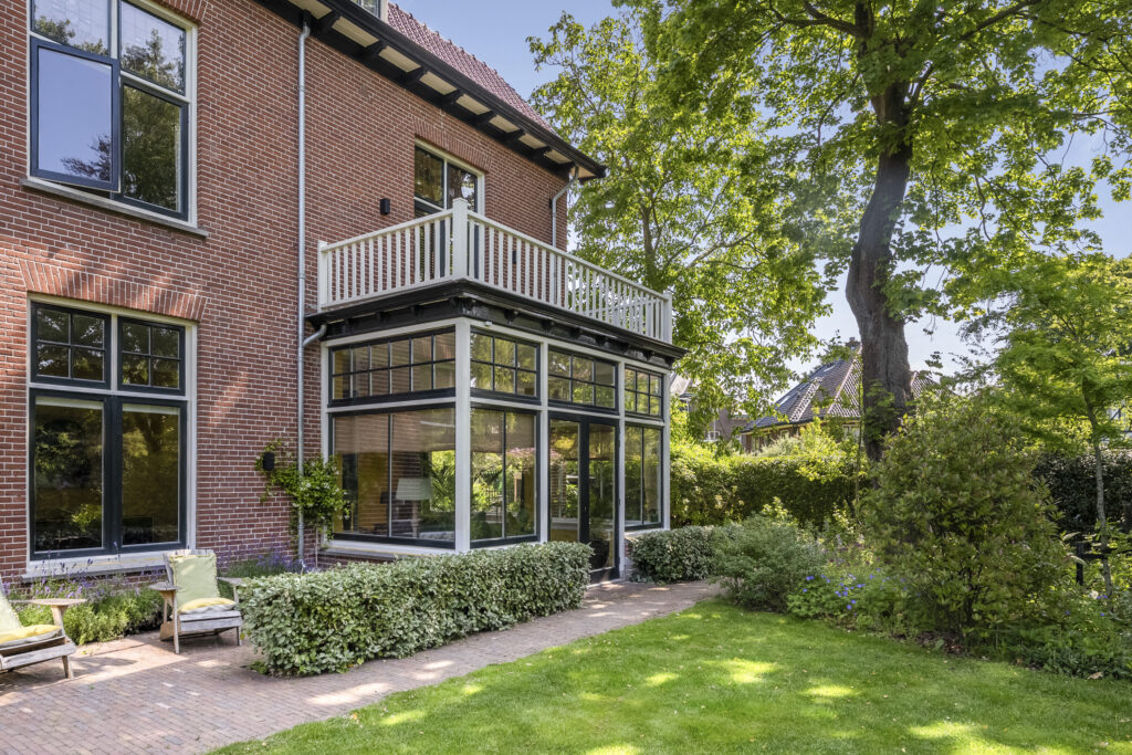 Brick house with porch, lush garden view
