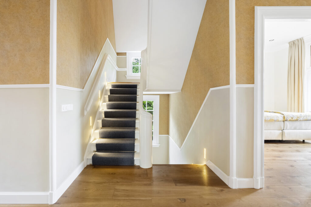 Modern staircase with carpet and wall lighting.