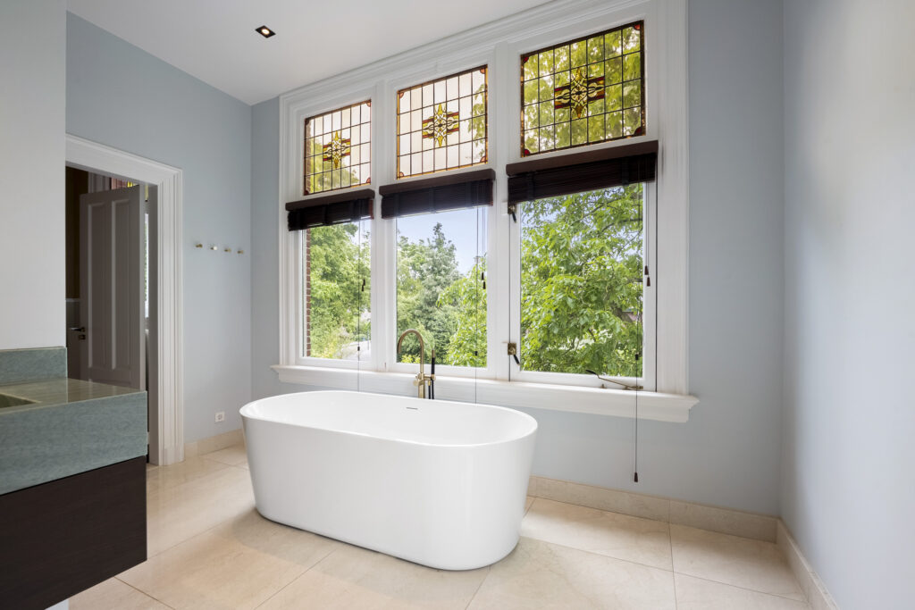 Modern bathroom with freestanding tub and large window.