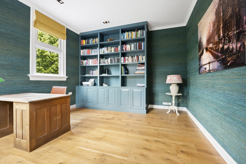 Home office with teal bookshelf and wooden desk.
