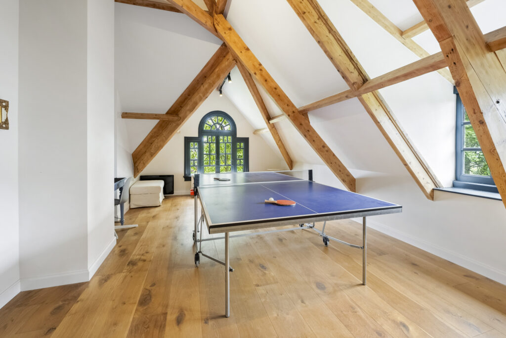 Attic with ping pong table and wooden beams.