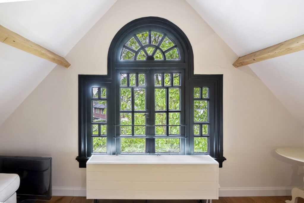 Sunny attic room with arched window.