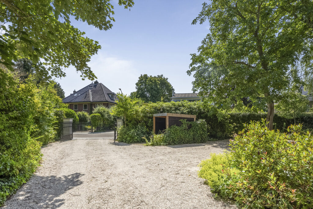 Gated entrance to a house surrounded by greenery.