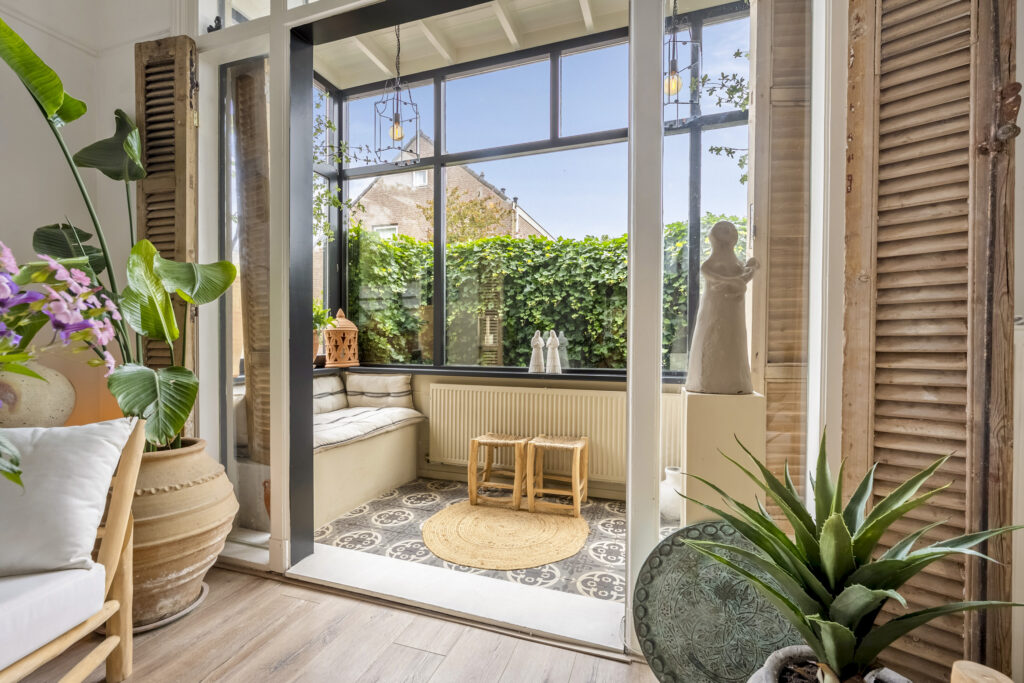 Cozy sunroom with plants and seating, outdoors.