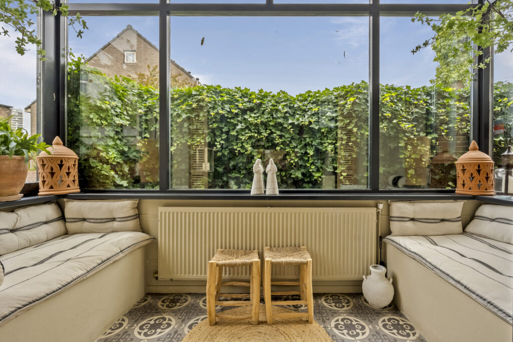 Cozy sunroom with plants and rustic decor.