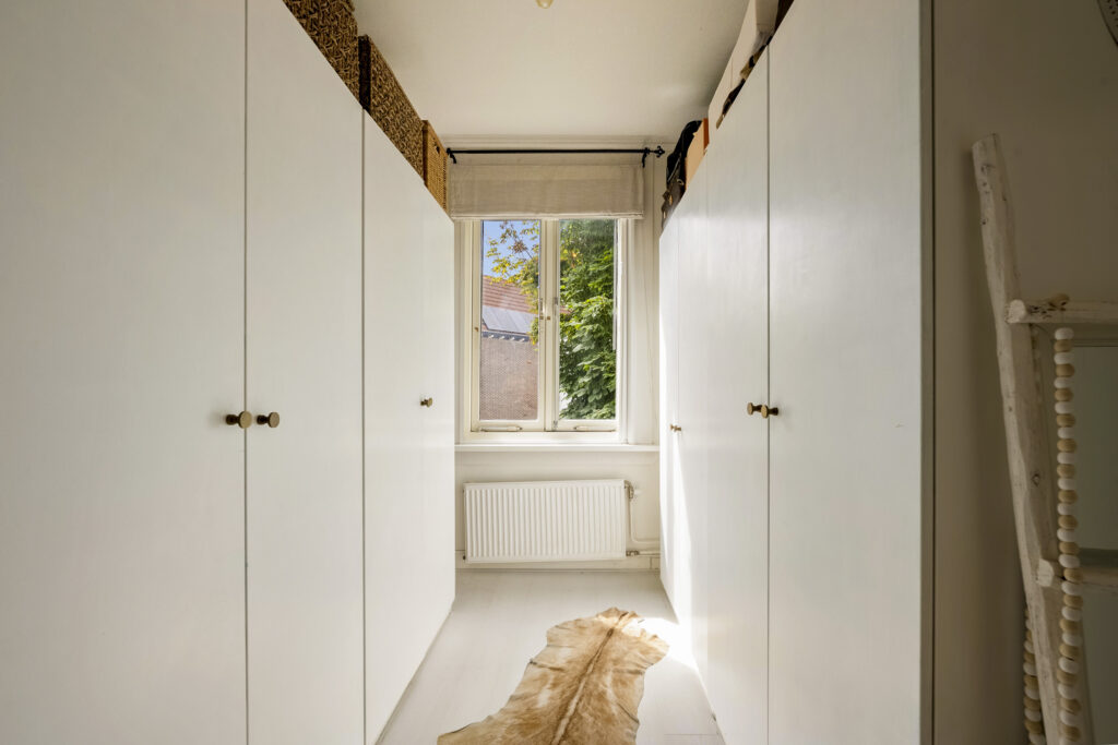 Narrow hallway with white cabinets and window view.