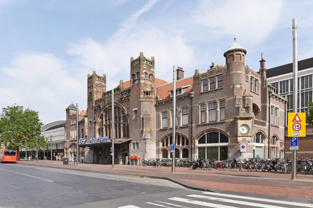 Historic Haarlem train station with bicycles parked outside.