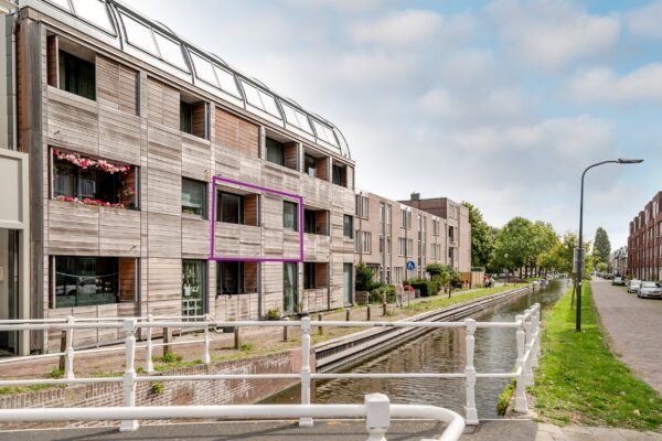 Modern building by canal with trees and sky