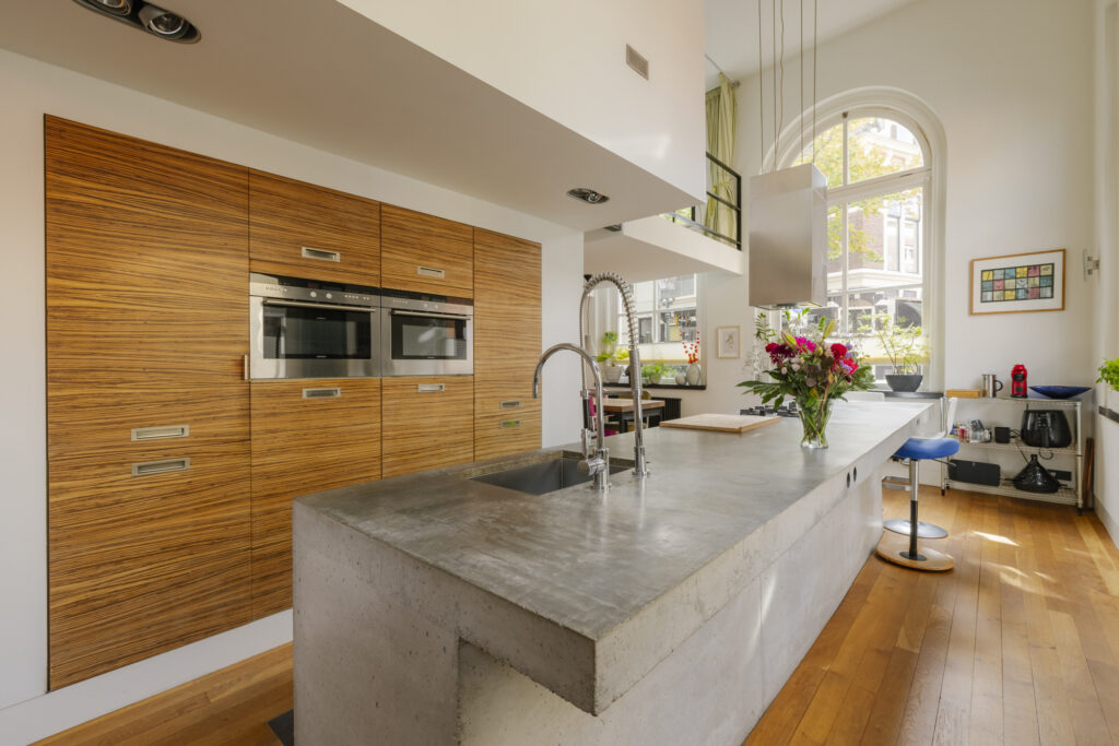 Modern kitchen with wood cabinets and concrete countertop.