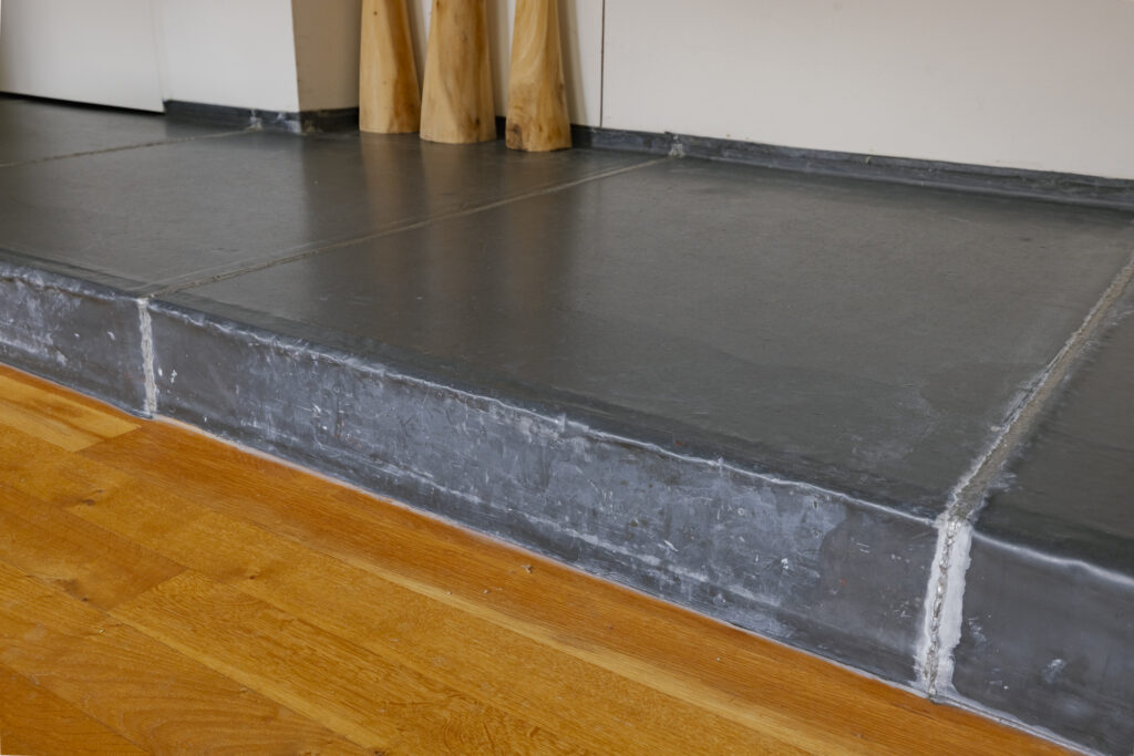 Gray metal doorstep on wooden floor background.