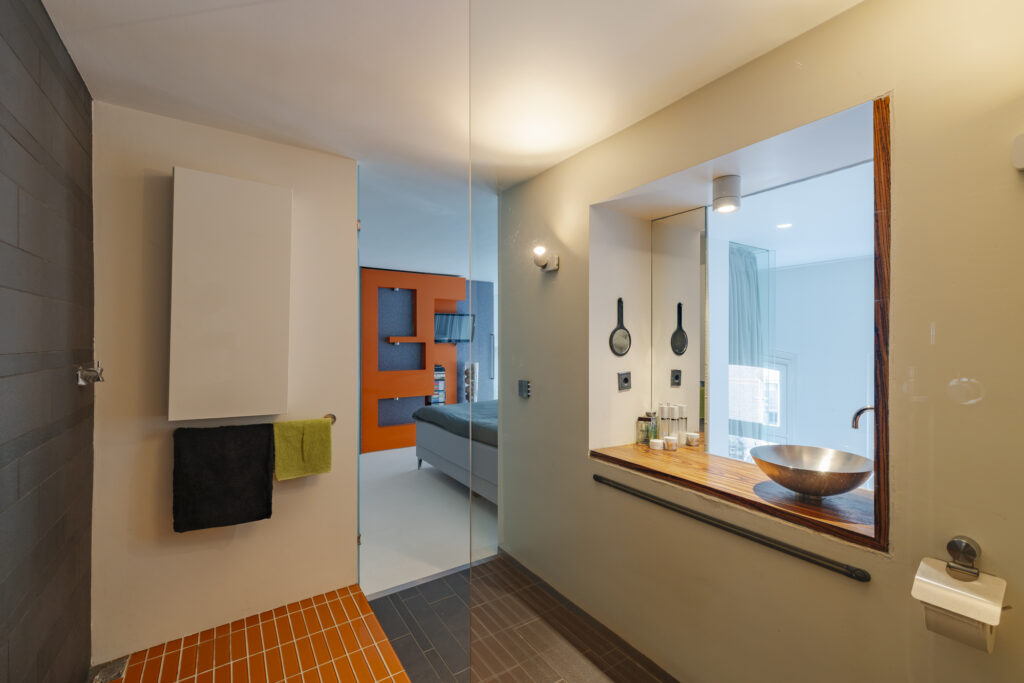 Modern bathroom with glass partition and wooden countertop.