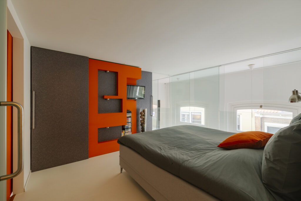 Modern bedroom with orange and gray accents.