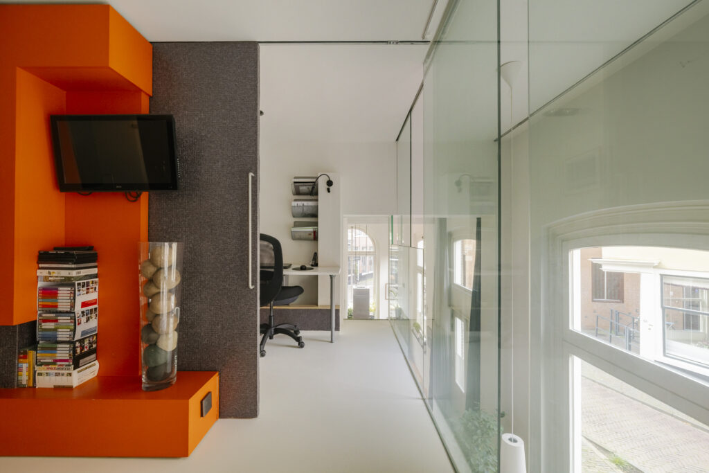 Modern interior with orange accents and glass walls.