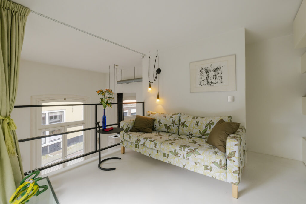 Modern living area with floral couch and pendant lights.