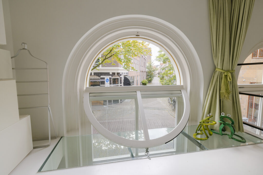 Round window view with green curtains and decor.
