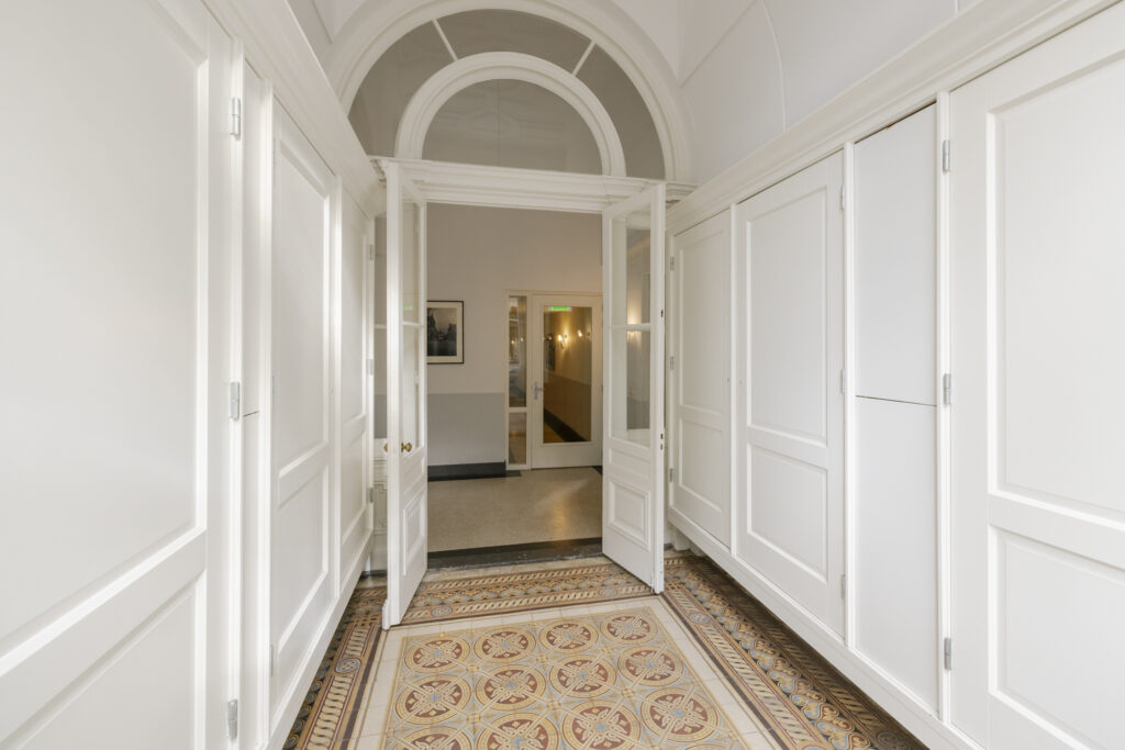 Bright hallway with open white doors and tiles.