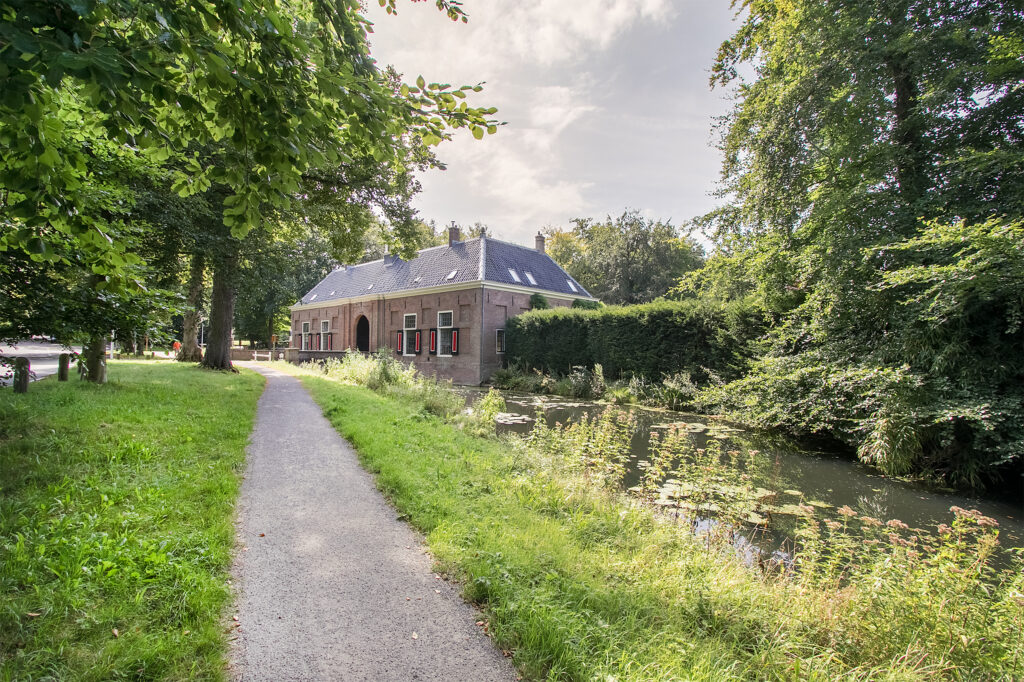 Historic house by a lush, tree-lined pathway