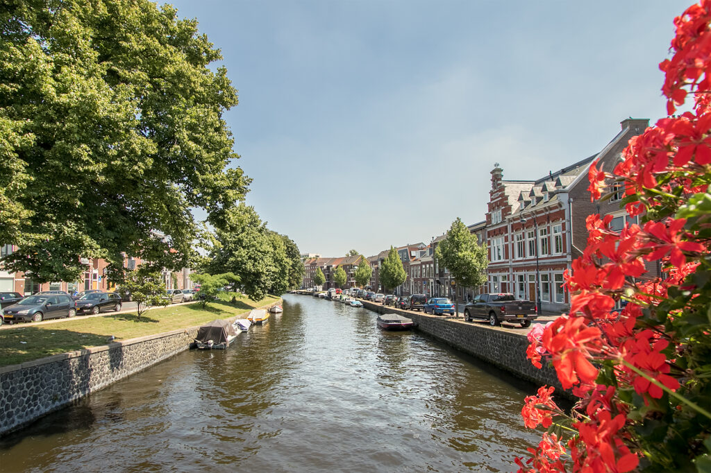 Scenic canal with buildings and flowers, sunny day.