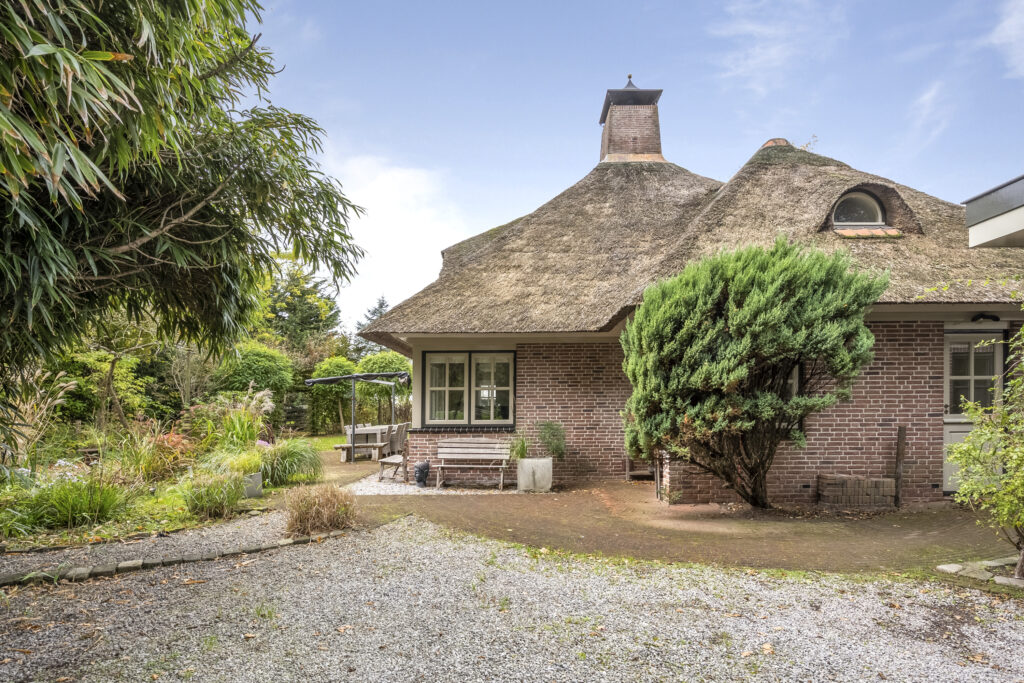 Charming house with thatched roof in lush garden