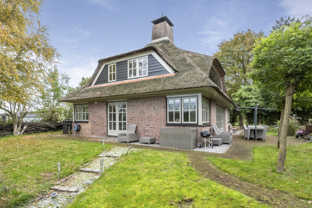 Charming brick house with thatched roof in garden.